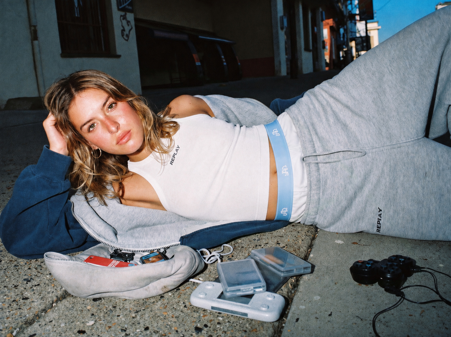 Model reclining in a white tank and Action Replay boxers with retro handheld devices and controller props.